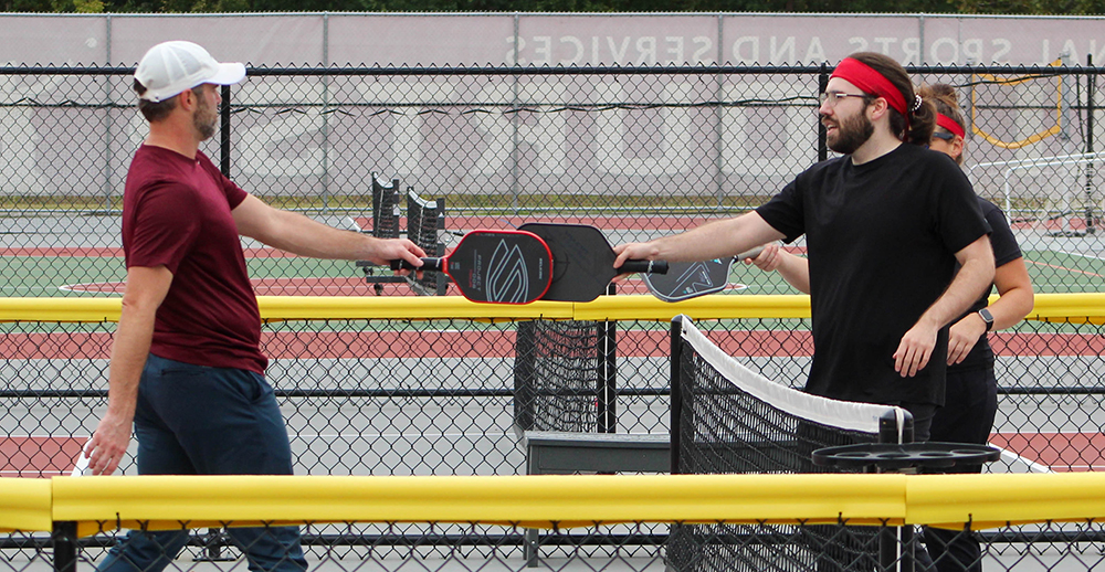 Pickleball participants return a ball during a game